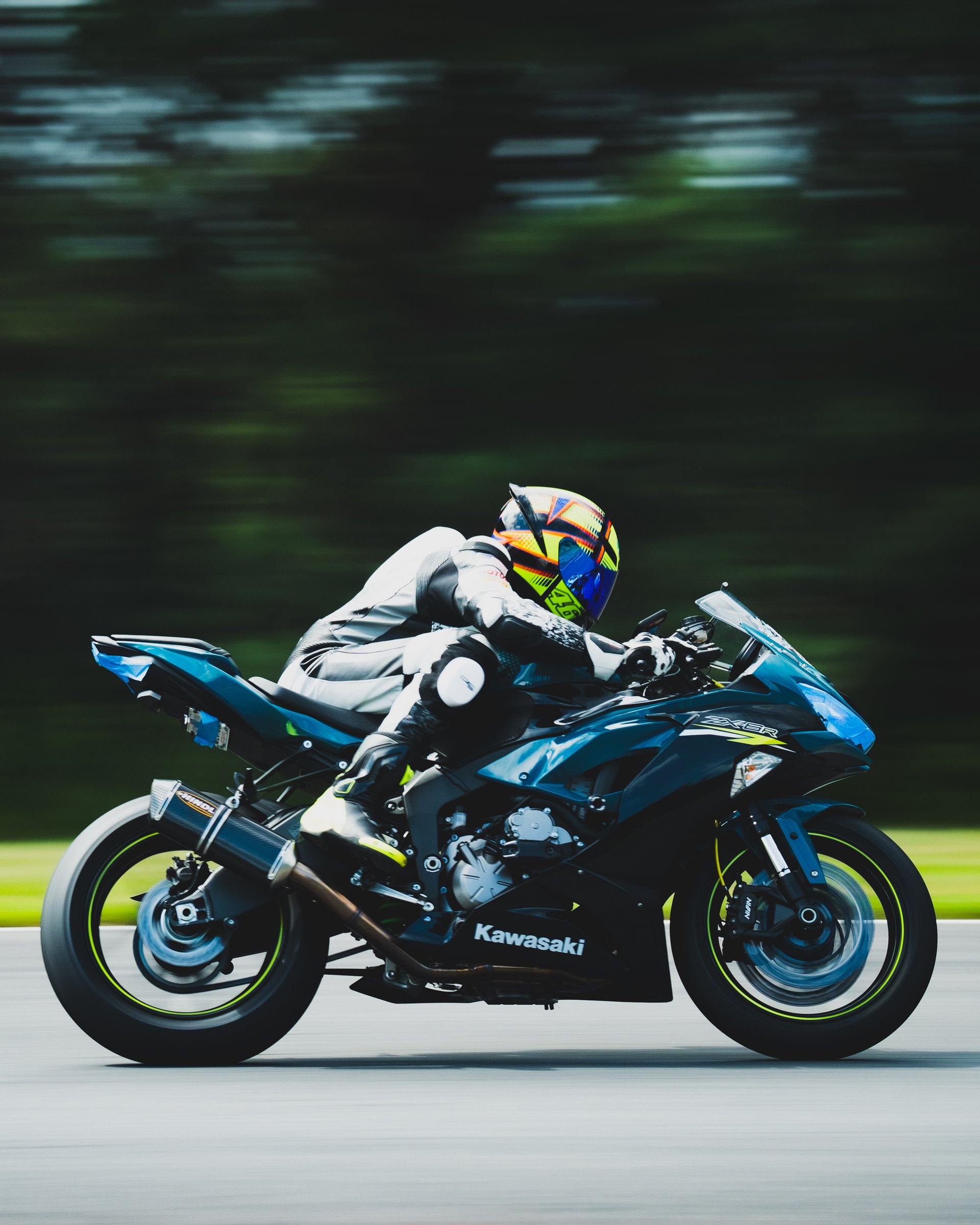 Rider tucked in on a blue Kawasaki ZX-6R, panned at speed