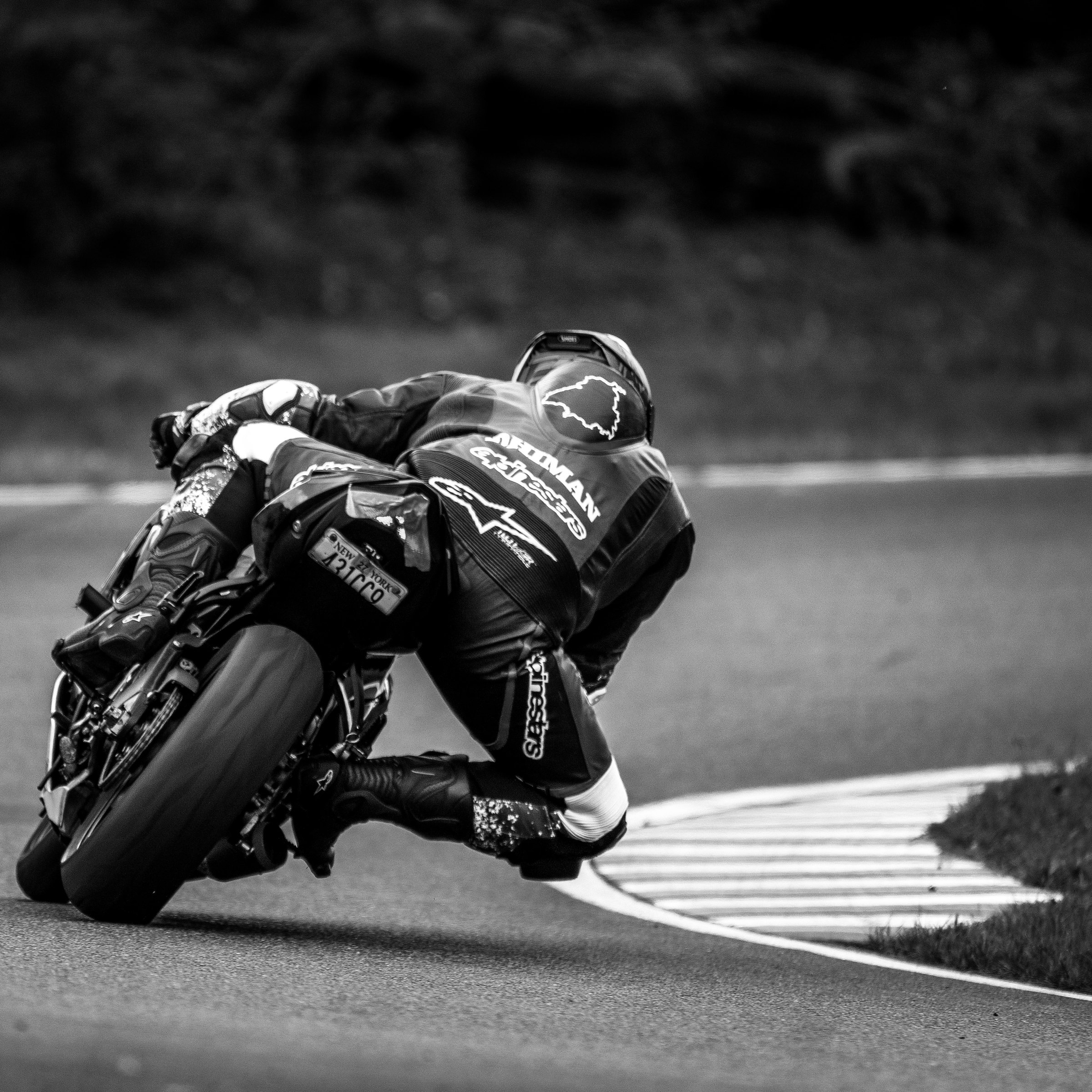 Rider from behind, knee down toward the curbing, in black and white