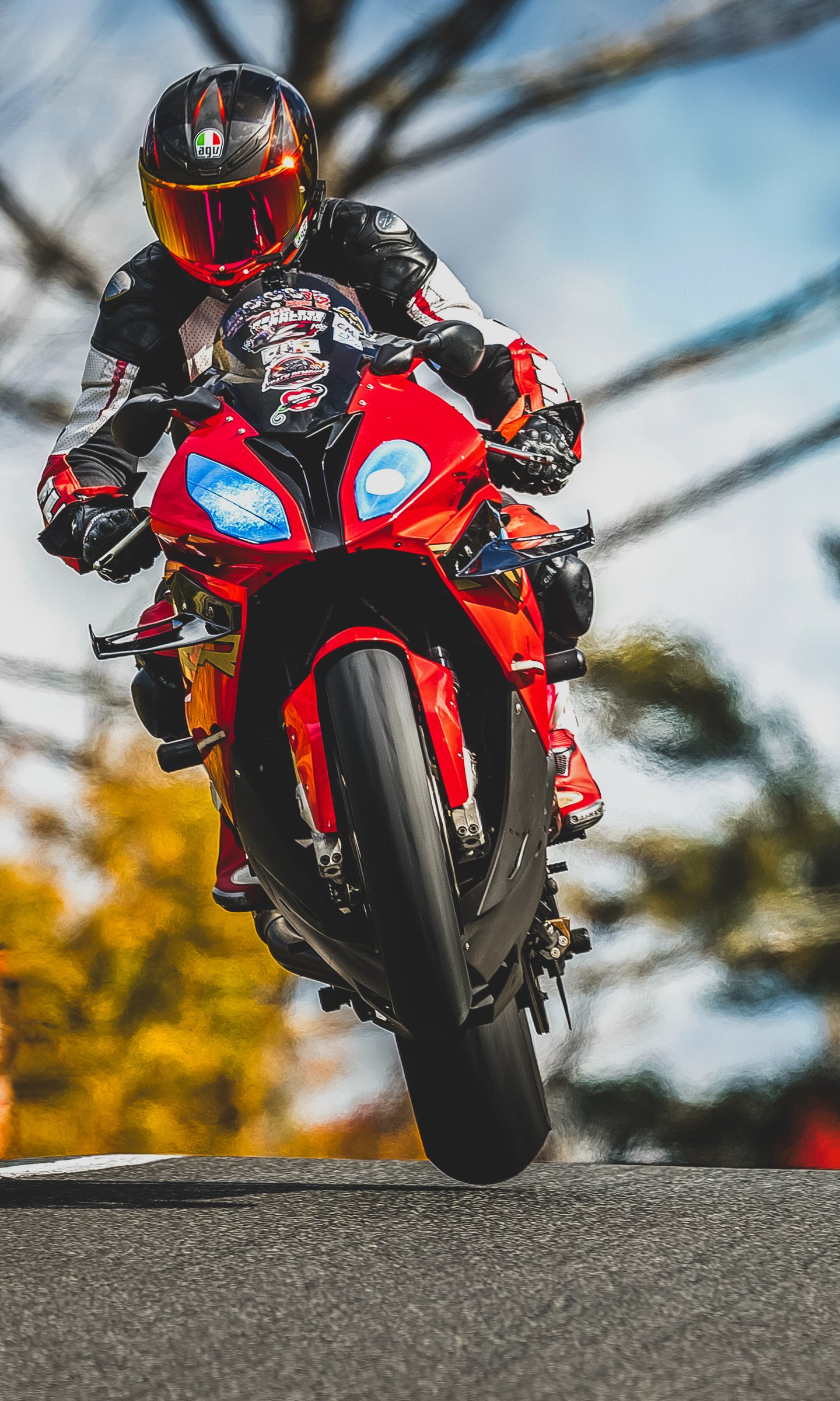 Rider on a red BMW lifting the front wheel, head on